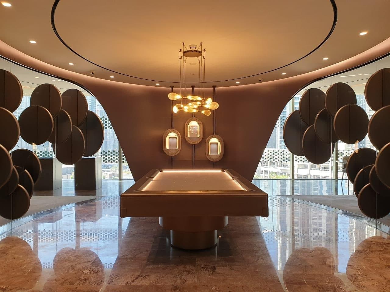 A finished living room with a stone fireplace, cream seating and a round dark table